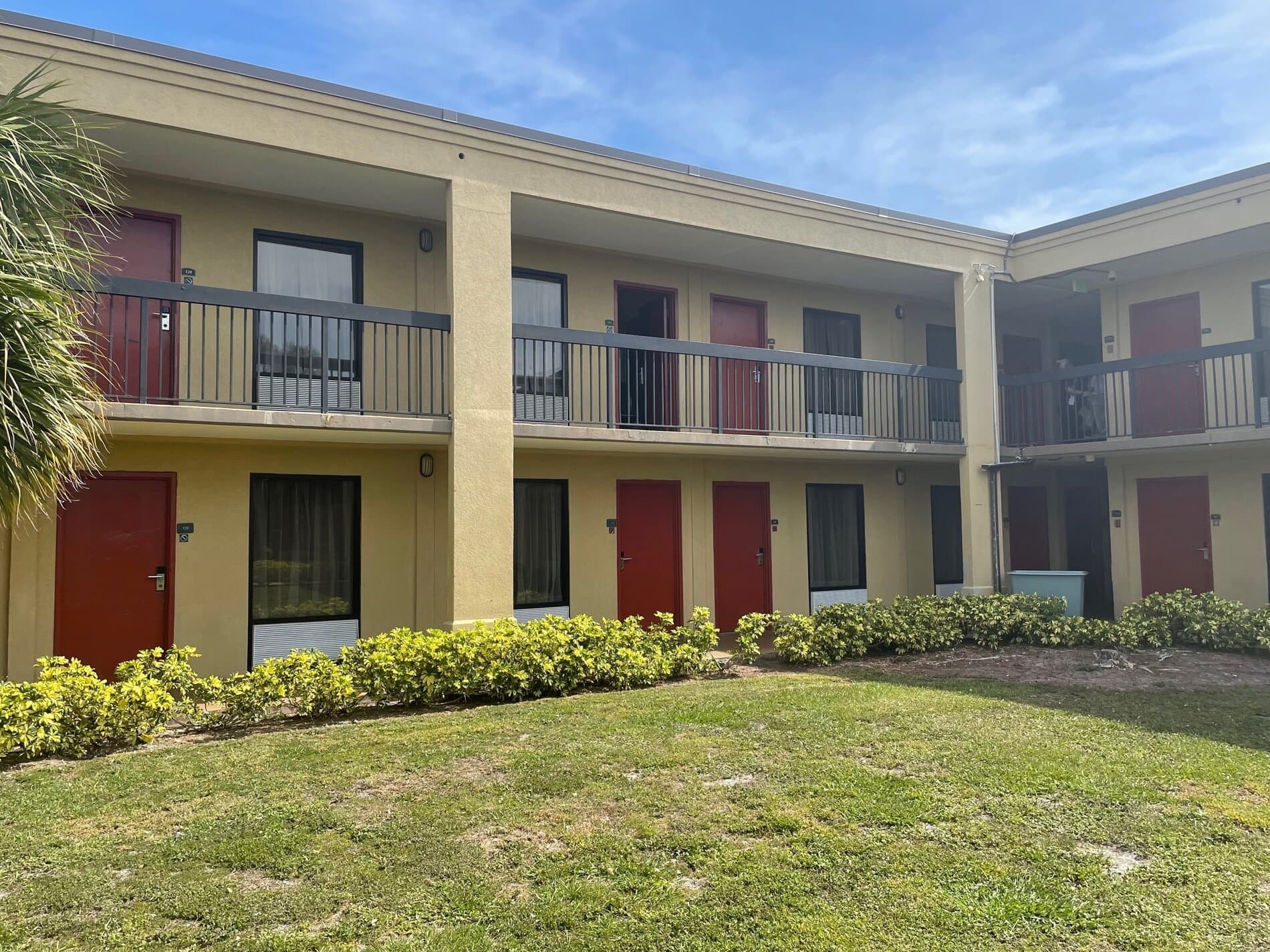 The courtyard corner before conversion: yellow stucco, red doors and dark railings on the two-story motel building