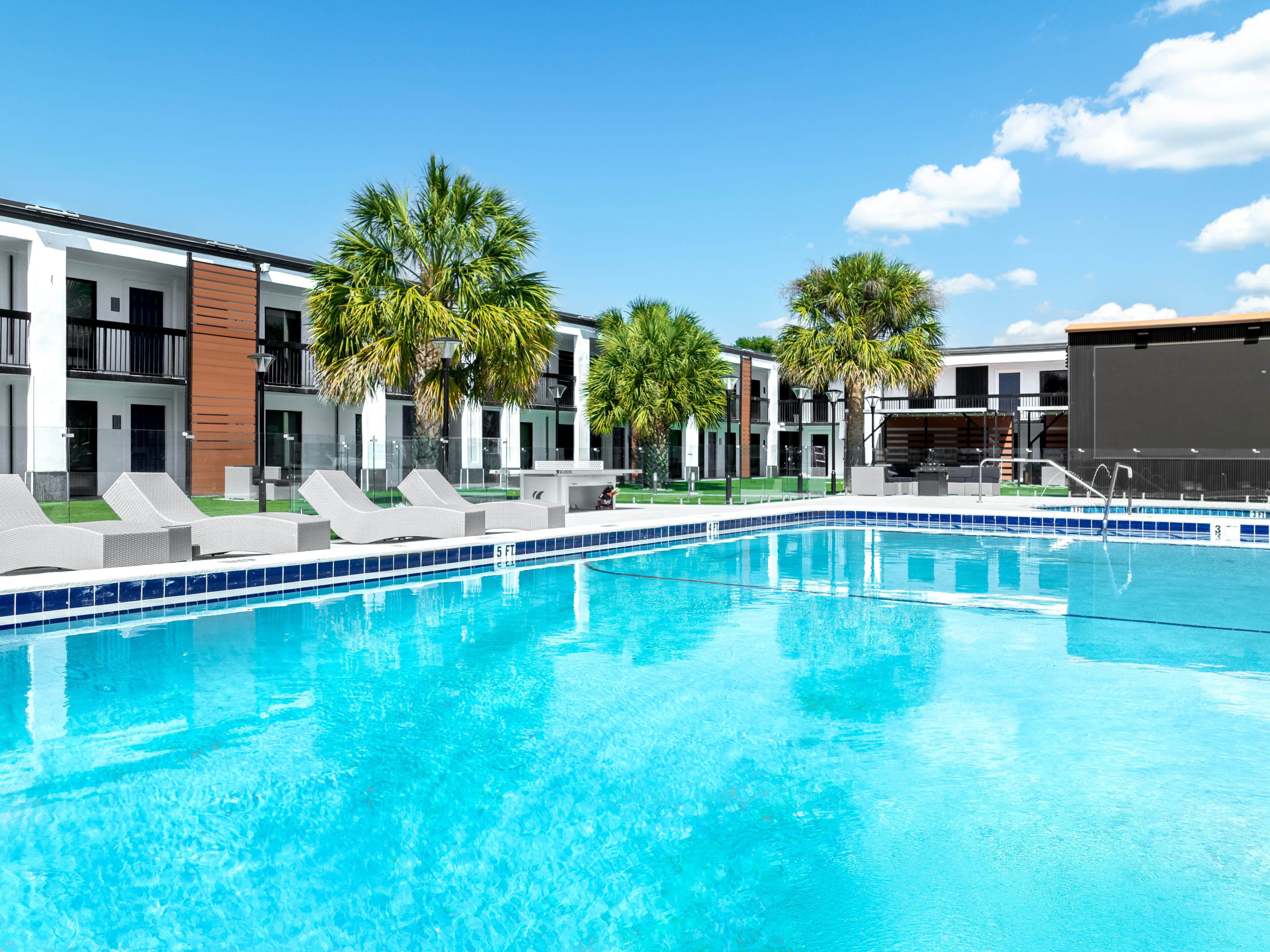 The resort pool at The Jade Winter Haven after conversion, with loungers, palms and the outdoor theater screen