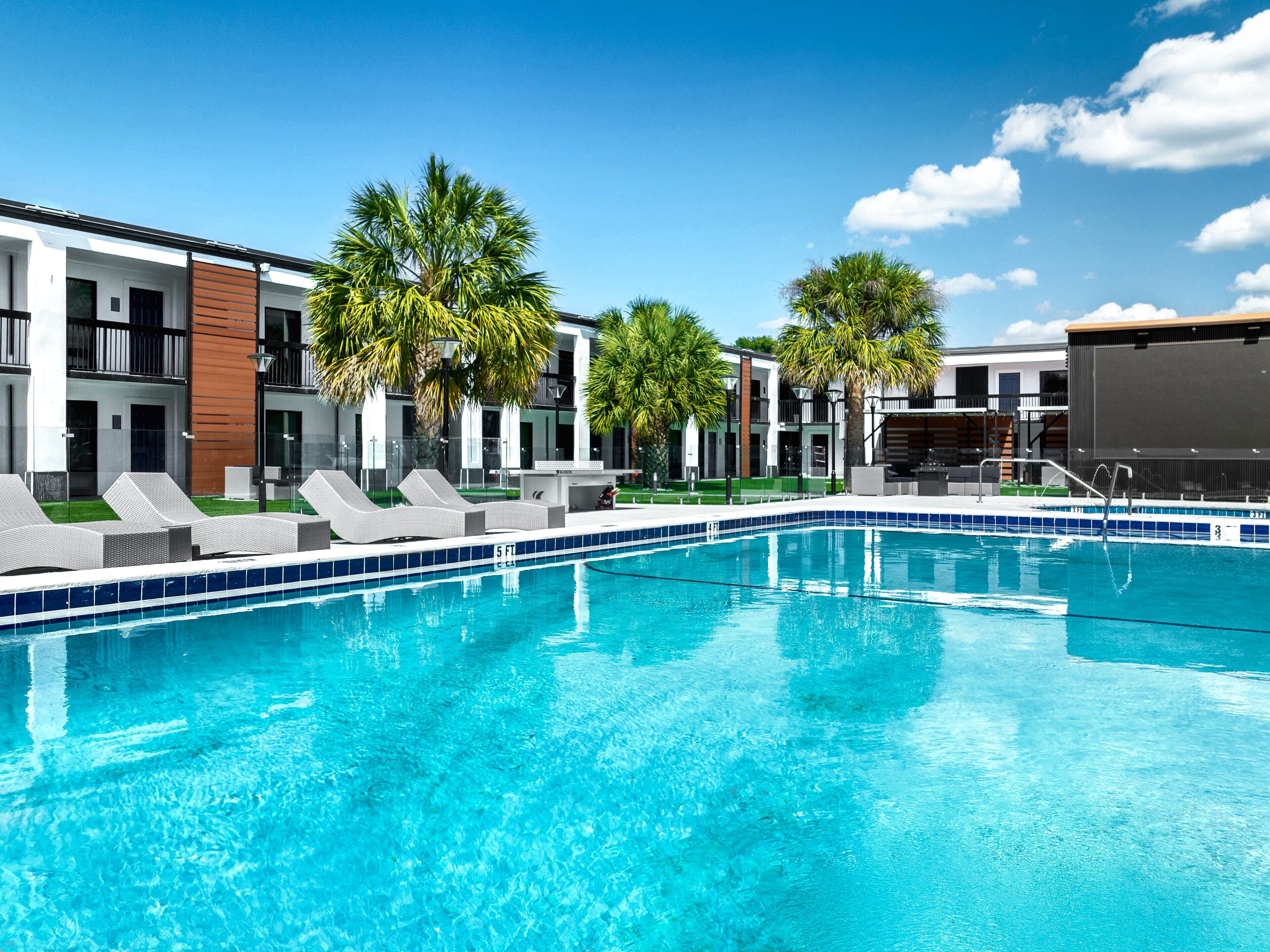 The resort pool at The Jade Winter Haven after conversion, with loungers, palms and the outdoor theater screen