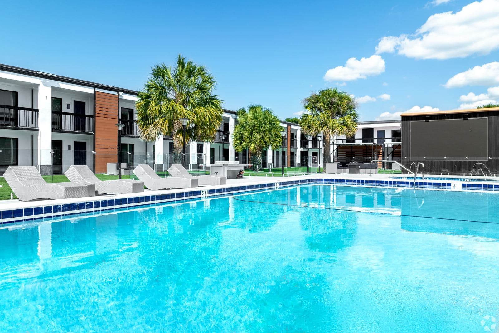 The resort pool at The Jade Winter Haven: turquoise water, loungers, palms, and the converted apartment buildings behind