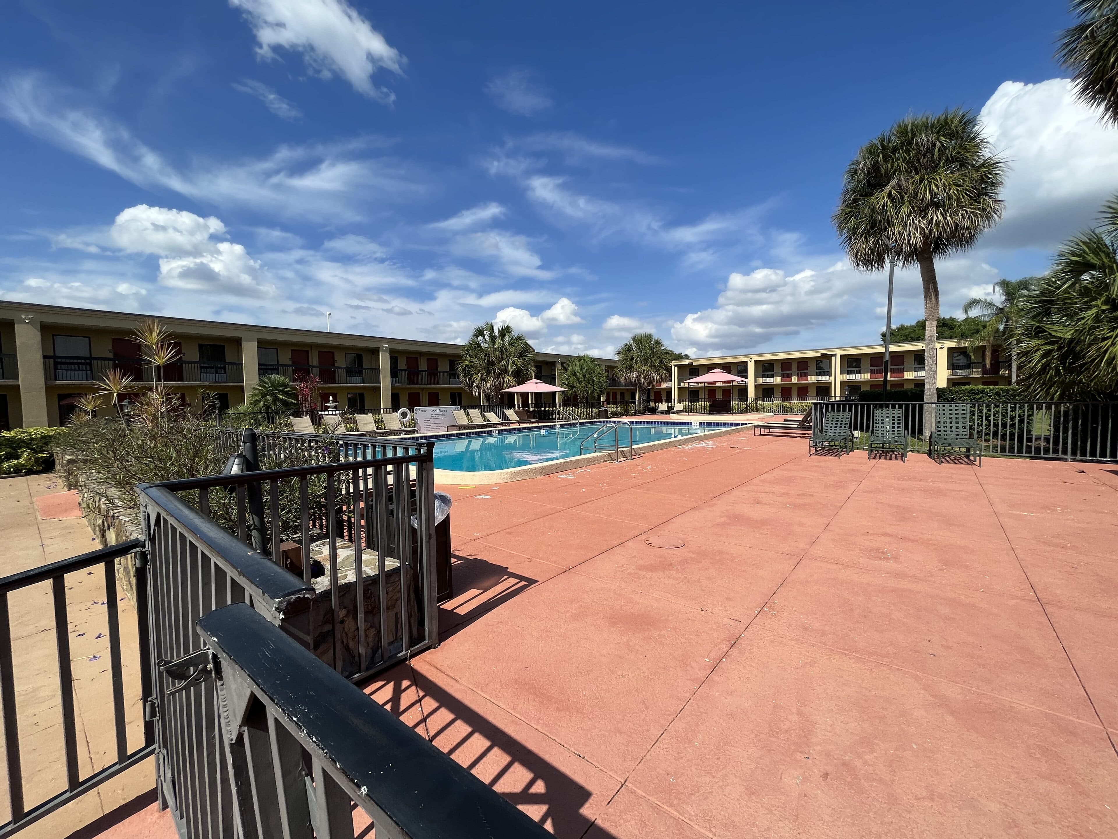 The hotel pool deck before conversion: dated railings, worn deck, the motel buildings behind