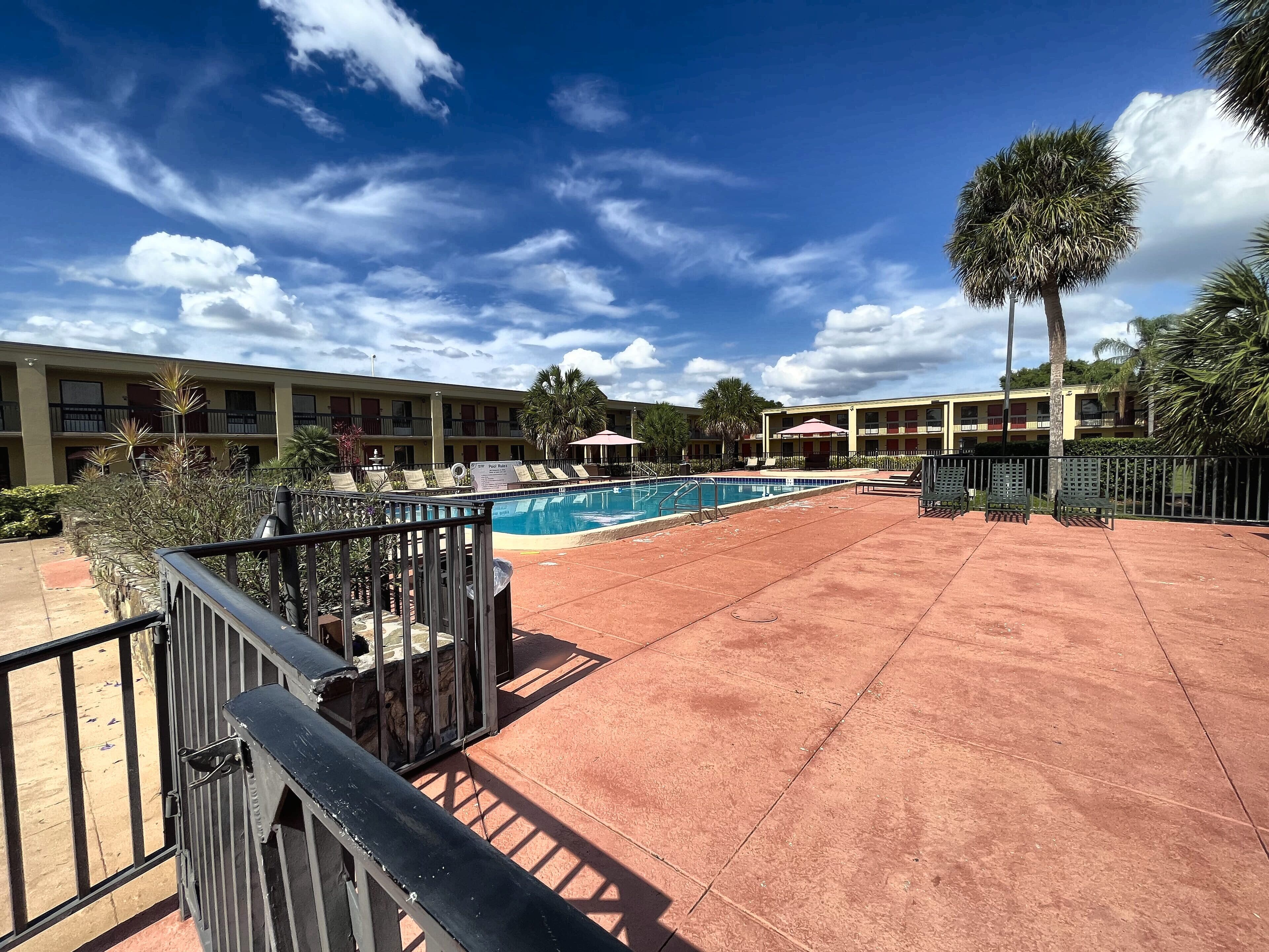 The hotel pool deck before conversion: dated railings, worn deck, the motel buildings behind