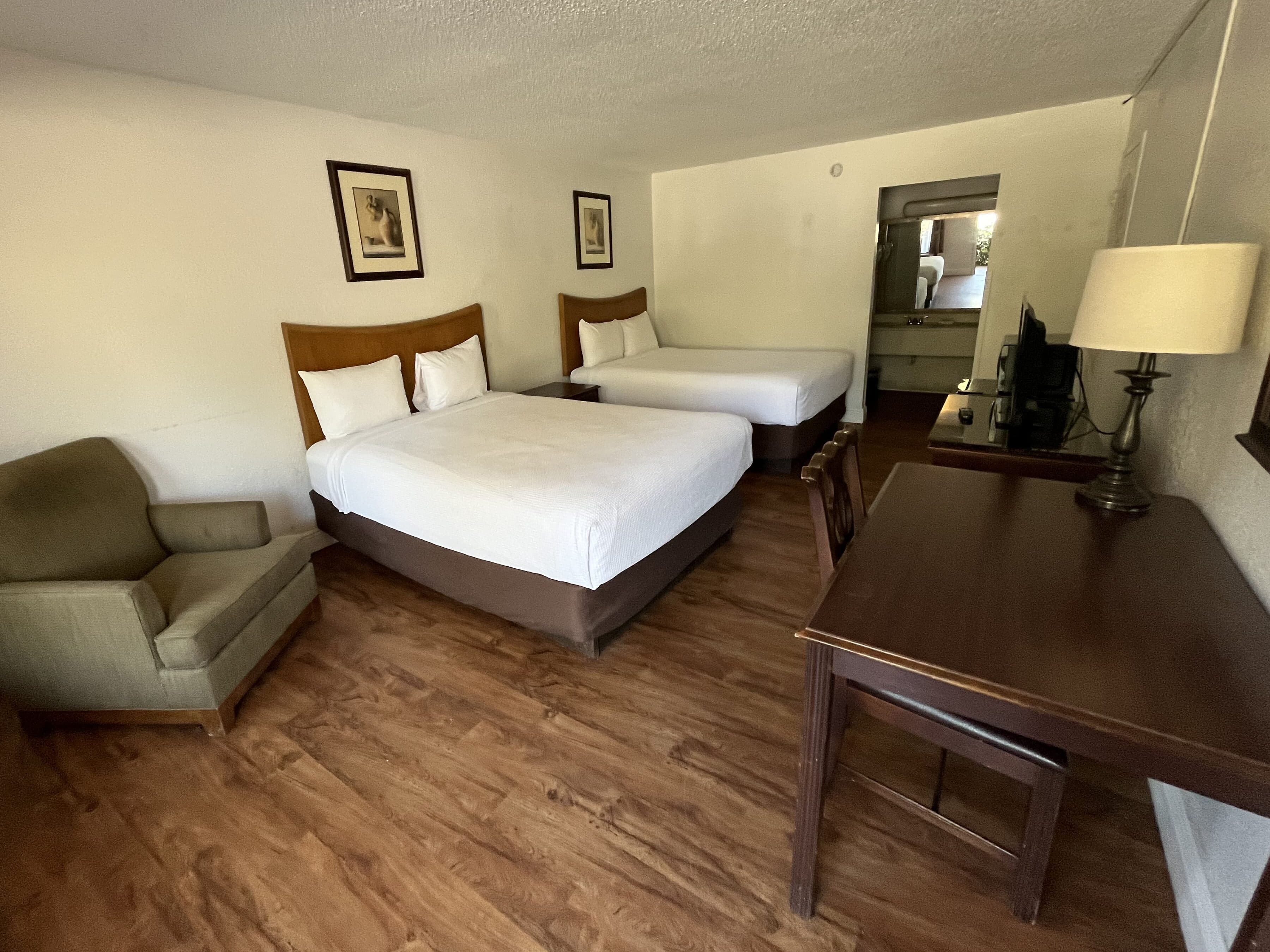 A hotel room before conversion: two double beds, dated furniture and finishes